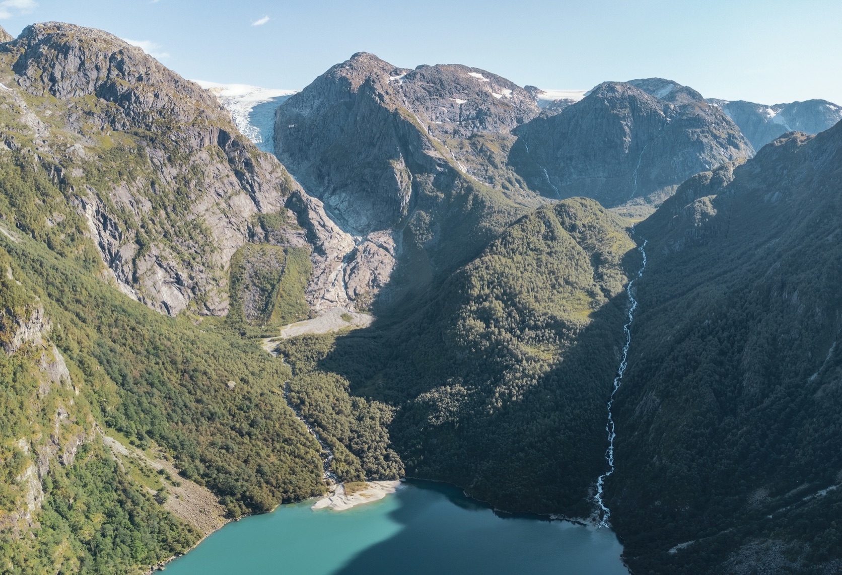 Bondhusdalen sett ovenfra, med turkist vann nederst og Bondhusbreen mellom fjellene innerst i dalen